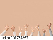 Многие руки показывают жест "ОК" на бежевом фоне. Стоковое фото, фотограф Pixel_shot / Фотобанк Лори