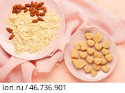 Тарелки с вкусными марципановыми конфетами, миндальными хлопьями и орехами на цветном столе. Стоковое фото, фотограф Pixel_shot / Фотобанк Лори