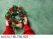 Женские руки с красивым венком из омелы на зеленом фоне с эффектом состаривания. Стоковое фото, фотограф Pixel_shot / Фотобанк Лори