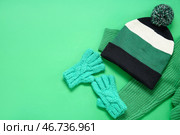 Вязанные теплые перчатки, шапка и свитер на зеленом фоне. Стоковое фото, фотограф Pixel_shot / Фотобанк Лори