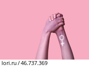 Женщина держит свои раскрашенные руки на розовом фоне. Концепция феминизма. Стоковое фото, фотограф Pixel_shot / Фотобанк Лори