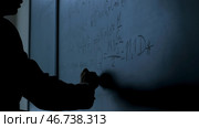 Hand with chalk wrote physics formulas on black chalkboard closeup. Стоковое фото, фотограф David Kashakhi / Фотобанк Лори