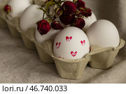 Яйца пасхальные раскрашенные в картонной упаковке, украшенные сухоцветом красной розы. Стоковое фото, фотограф Оксана Шведкова / Фотобанк Лори