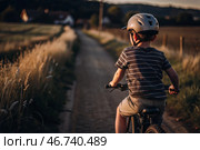 A cheerful little boy rides a bicycle in a helmet outdoors. A happy child is engaged in an active sport. Protection. Life insurance and child safety. Стоковое AI-изображение, AI-художник Photojuli / Фотобанк Лори