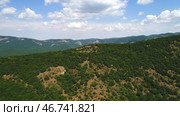 Amazing endless landscape of the high mountain ranges covered by green trees and shrubs against the blue cloudy sky in summer day. Стоковое фото, фотограф David Kashakhi / Фотобанк Лори