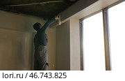 Painter working with paint roller to paint the wall of a room. Стоковое фото, фотограф David Kashakhi / Фотобанк Лори