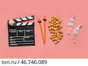 Композиция с вкусным карамельным попкорном, мегафоном, черепом, скелетами и трубочками для Хэллоуинского празднования на коралловом фоне. Стоковое фото, фотограф Pixel_shot / Фотобанк Лори