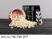 Перевернутый ведро с попкорном, хэллоуинскими украшениями и кинематографическим клапаном на деревянном столе на сером фоне. Стоковое фото, фотограф Pixel_shot / Фотобанк Лори