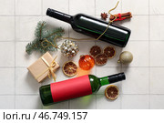 Бутылки вина с сушенным апельсином, различными специями и новогодней подарочной коробкой на белом плиточном фоне. Стоковое фото, фотограф Pixel_shot / Фотобанк Лори