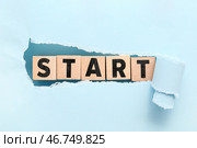 Кубики с словом START видимым через разорванную синюю бумагу. Стоковое фото, фотограф Pixel_shot / Фотобанк Лори