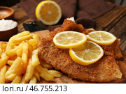 Доска с вкусной жареной треской с картофельными дольками и лимоном на деревянном фоне, крупным планом. Стоковое фото, фотограф Pixel_shot / Фотобанк Лори