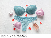 Сексуальное голубое нижнее белье с воздушными шариками в форме сердец и духами на белом текстурированном фоне. Празднование Дня святого Валентина. Стоковое фото, фотограф Pixel_shot / Фотобанк Лори