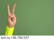 Женская рука, показывающая жест мира на зеленом фоне, крупным планом. Стоковое фото, фотограф Pixel_shot / Фотобанк Лори