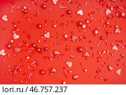 Сладкие разноцветные конфетти рассыпаны на красном фоне. Стоковое фото, фотограф Pixel_shot / Фотобанк Лори