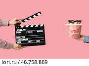 Руки с хлопушкой, ведром попкорна и 3D-очками на розовом фоне. Стоковое фото, фотограф Pixel_shot / Фотобанк Лори