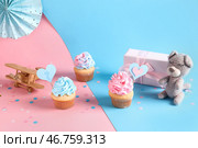 Вкусные кексы в подарочной коробке, украшения и игрушки на цветном фоне. Концепция вечеринки для раскрытия пола ребенка. Стоковое фото, фотограф Pixel_shot / Фотобанк Лори