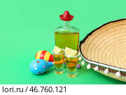 Композиция с маракасами, сомбреро, лаймом, бутылкой и шотами текилы на зеленом фоне. Стоковое фото, фотограф Pixel_shot / Фотобанк Лори