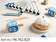 Izraelskiy sladkiy pirog - Sufganiyah, svechi, menorah i draydely na belom stole. Стоковое фото, фотограф Pixel_shot / Фотобанк Лори