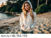 Beautiful young woman in a white hoodie on the beach. Template layout for hoodie design, print area layout for logo or design. Стоковое AI-изображение, AI-художник Photojuli / Фотобанк Лори