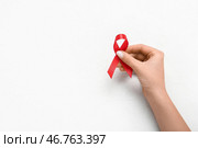 Женская рука с красной лентой на белом гранжевом фоне. Концепция дня борьбы со СПИДом. Стоковое фото, фотограф Pixel_shot / Фотобанк Лори