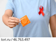 Женщина в футболке с презервативом и красной лентой, крупный план. Концепция Дня борьбы со СПИДом. Стоковое фото, фотограф Pixel_shot / Фотобанк Лори