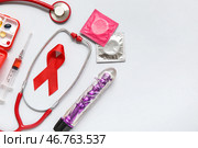 Красная лента с стетоскопом, презервативами, шприцем и вибратором на светлом фоне. День борьбы со СПИДом. Стоковое фото, фотограф Pixel_shot / Фотобанк Лори