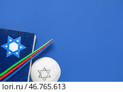 Композиция Хануки с Торой, свечами и кипой на синем фоне. Стоковое фото, фотограф Pixel_shot / Фотобанк Лори