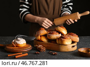 Женщина готовит вкусные корицей булочки на черном фоне. Стоковое фото, фотограф Pixel_shot / Фотобанк Лори