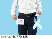 Молодой бизнесмен держит бумагу с надписью SOS и голубой лентой на цветном фоне, крупным планом. Концепция осведомленности о раке предстательной железы. Стоковое фото, фотограф Pixel_shot / Фотобанк Лори
