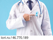 Мужской врач указывает на голубую ленту на цветном фоне, крупным планом. Концепция осведомленности о раке простаты. Стоковое фото, фотограф Pixel_shot / Фотобанк Лори
