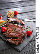 Грифельная тарелка со вкусным нарезанным жареным мясом, помидорами, специями и зеленью на деревянном столе. Стоковое фото, фотограф Pixel_shot / Фотобанк Лори