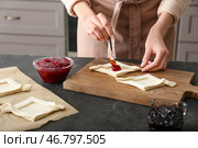 Женщина наполняет датское печенье фруктовым джемом на кухонном столе. Стоковое фото, фотограф Pixel_shot / Фотобанк Лори