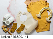 Композиция с детской одеждой, слюнявчиком, игрушками и обувью на светлом фоне. Стоковое фото, фотограф Pixel_shot / Фотобанк Лори