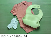 Детская одежда и слюнявчик на цветном деревянном фоне. Стоковое фото, фотограф Pixel_shot / Фотобанк Лори