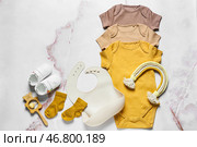 Композиция с детской одеждой, слюнявчиком, игрушками и обувью на светлом фоне. Стоковое фото, фотограф Pixel_shot / Фотобанк Лори