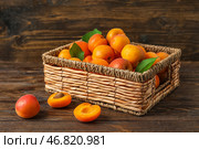 Корзина из искусственного материала с свежими абрикосами на деревянном фоне. Стоковое фото, фотограф Pixel_shot / Фотобанк Лори