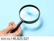 Женская рука с увеличителем на синем фоне. Стоковое фото, фотограф Pixel_shot / Фотобанк Лори