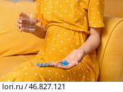 Молодая беременная женщина с стаканом воды и таблетками фолиевой кислоты дома, крупным планом. Стоковое фото, фотограф Pixel_shot / Фотобанк Лори