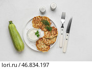 Тарелка вкусных кабачковых оладий с сметаной на светлом фоне. Стоковое фото, фотограф Pixel_shot / Фотобанк Лори