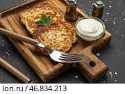 Деревянная доска с вкусными кабачковыми оладьями с сметаной на грунтовом фоне. Стоковое фото, фотограф Pixel_shot / Фотобанк Лори
