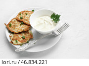 Тарелка вкусных кабачковых оладий с сметаной на светлом фоне. Стоковое фото, фотограф Pixel_shot / Фотобанк Лори