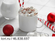 Чашка горячего какао с маршмеллоу и рождественскими шариками на белом плиточном фоне. Стоковое фото, фотограф Pixel_shot / Фотобанк Лори
