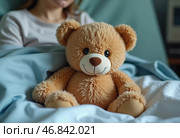 Encased in a hospital bed, a woman finds solace in her teddy bear, symbolizing hope. The soft toy stands as a silent companion amidst the challenges of recovery and illness. Стоковое AI-изображение, AI-художник Юлия Петровская / Фотобанк Лори