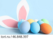 Покрашенные пасхальные яйца и бумажные кроличьи уши на синем фоне, крупным планом. Стоковое фото, фотограф Pixel_shot / Фотобанк Лори