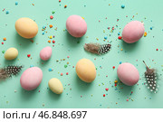 Покрашенные пасхальные яйца с перьями на бирюзовом фоне. Стоковое фото, фотограф Pixel_shot / Фотобанк Лори