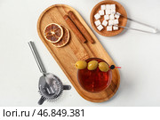 Деревянная доска с бокалом вкусного коктейля "Олдфэшн", оливками и палочками корицы на белом фоне. Стоковое фото, фотограф Pixel_shot / Фотобанк Лори