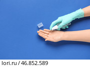 Женщина наносит дезинфицирующее средство на руки на фоне голубого цвета. Стоковое фото, фотограф Pixel_shot / Фотобанк Лори