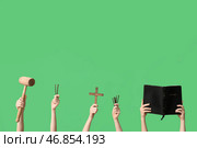 Женские руки с Священной Библией, крестом, молотом и гвоздями на зеленом фоне. Концепция Благой Пятницы. Стоковое фото, фотограф Pixel_shot / Фотобанк Лори