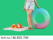 Молодая женщина с надувным кругом, полотенцем и наушниками на зеленом фоне. Концепция летних каникул. Стоковое фото, фотограф Pixel_shot / Фотобанк Лори