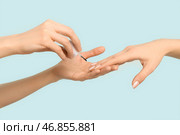 Женские руки, держащие кисть с маслом для кутикулы на голубом фоне. Стоковое фото, фотограф Pixel_shot / Фотобанк Лори